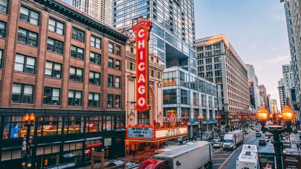 Chicago Theatre sign in downtown Chicago, surrounded by historic and modern buildings with busy streets and city lights.