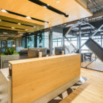 Modern coworking space reception with wooden desk, open ceiling, and industrial-style design.