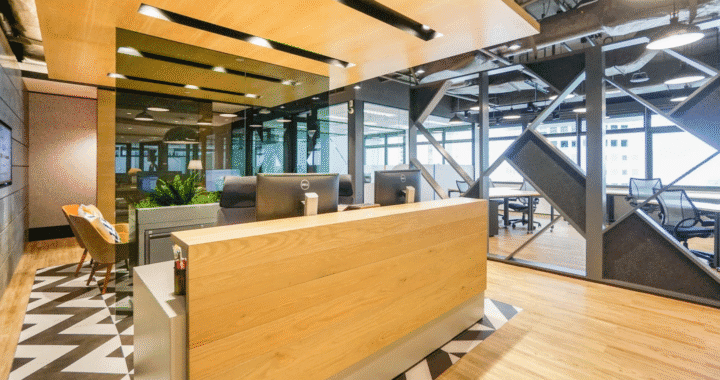 Modern coworking space reception with wooden desk, open ceiling, and industrial-style design.
